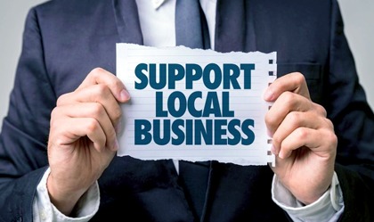 Business man holding a sign which reads "Support Local Business"